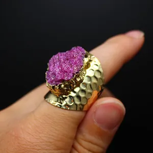 Close-up detail of a vibrant pink druzy crystal ring featuring a hammered gold band.