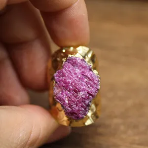 Close-up detail of raw purple ruby stone on a textured wide gold ring band