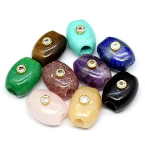 Close-up detail of assorted natural stone barrel beads featuring golden zircon inlays