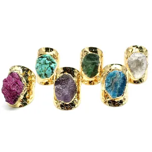 Detailed collection view of raw natural gemstone rings with wide gold hammered bands
