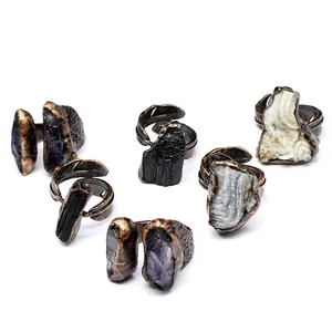 Detailed view of irregular raw natural stones set in vintage feather-patterned copper rings