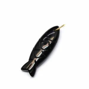Macro view of hand-carved black natural stone fish pendant with intricate scale details.