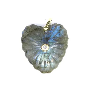 Dettaglio macro di un ciondolo in labradorite intagliato a cuore con zircone centrale