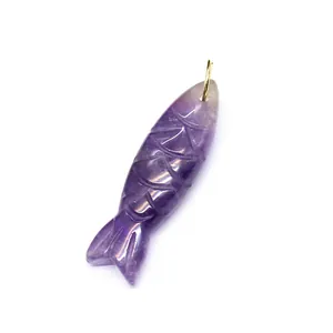 Macro detail of a hand-carved purple amethyst fish pendant with a gold bail