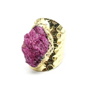 Macro detail of a raw magenta ruby gemstone set on a hammered wide gold finish ring