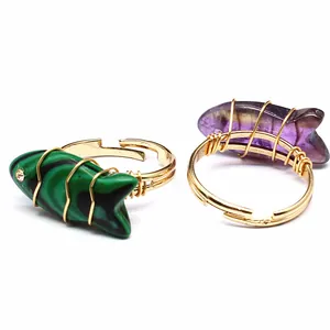 Detailed view of handmade wire-wrapped fish rings with green malachite and purple amethyst stones