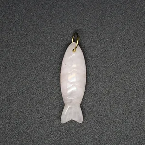 Detailed view of a hand-carved natural rose quartz fish pendant with a gold metal loop.