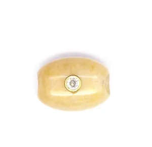 Detailed close-up of a natural stone barrel bead featuring an inlaid sparkling zircon