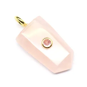 Nahaufnahme eines schildförmigen rosa Kristallanhängers mit einem kleinen Edelstein.