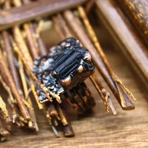 Close-up detail of a vintage handmade ring with black raw crystal and textured copper finish.