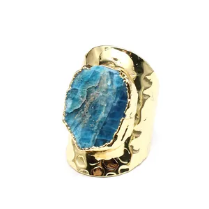 Close-up detail of wide hammered gold ring with a large blue raw crystal stone