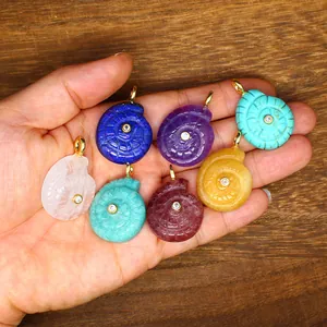 Variety of hand-carved natural stone sea snail pendants with central zircon inlay.