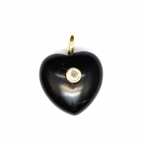 Gros plan détaillé d'un pendentif cœur en pierre noire avec un zircon scintillant.