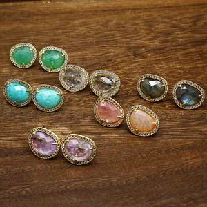 Close-up detail of various faceted natural stone stud earrings with crystal borders.