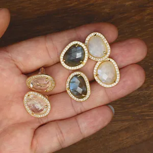 Detail of baroque style gold-plated earrings with natural stones and micro-pave crystal border.