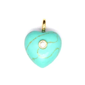 Gros plan d'un pendentif cœur en turquoise avec veines dorées et zircon incrusté