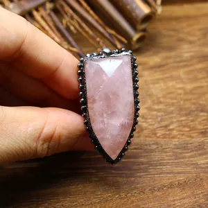 Primer plano de un anillo de escudo vintage con una piedra de cuarzo rosa facetada.