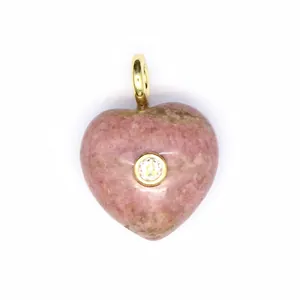 Gros plan d'un pendentif cœur en pierre naturelle rose avec zircon et bélière dorée.