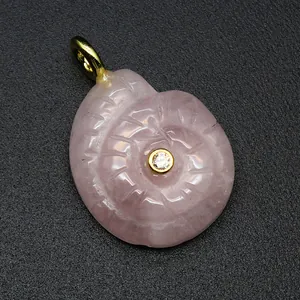 Detailed macro view of a pink carved natural stone conch pendant with inset zircon.