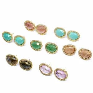 Macro detail of various baroque natural stone earrings with gold pavé borders.