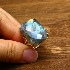 Close-up of a large rectangular faceted labradorite stone on a gold adjustable ring