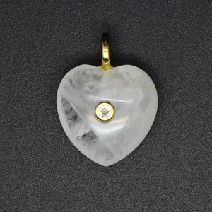 Gros plan d'un pendentif cœur en cristal blanc avec zircon serti en or.
