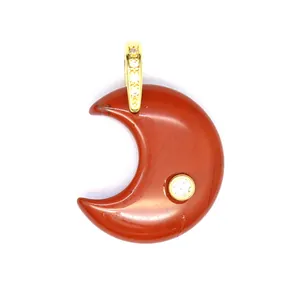 Macro detail of natural red stone crescent moon pendant with gold bail and zircon inlay