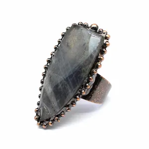 Primer plano de un anillo de escudo retro con labradorita tallada y banda de cobre envejecido.