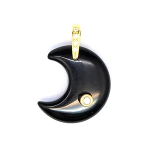 Detailed view of polished black stone crescent moon pendant with gold bail and zircon accents