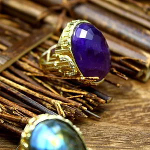 Detailed view of an oval faceted purple stone ring with ornate gold vintage band design
