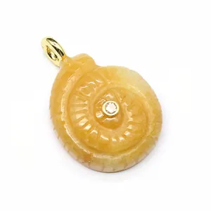 Close-up detail of carved yellow natural stone conch pendant with center zircon stone