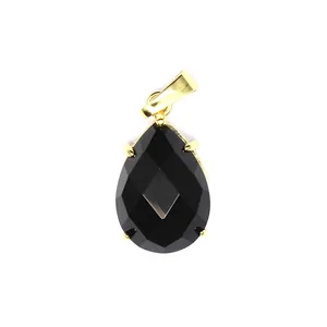 Vue macro d'un pendentif en pierre noire facettée en forme de poire avec monture dorée