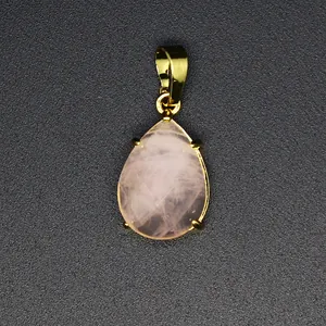 Vue macro d'un pendentif en pierre naturelle rose en forme de goutte facettée doré