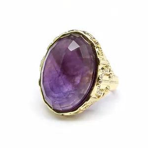 Close-up of a large oval purple crystal ring with vintage gold-tone carving
