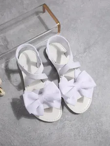 Detaillierte Draufsicht auf elegante weiße Sandalen mit großen dekorativen Schleifen.