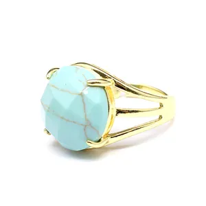 Detailaufnahme eines goldfarbenen Rings mit einem großen, facettierten Türkis-Stein.