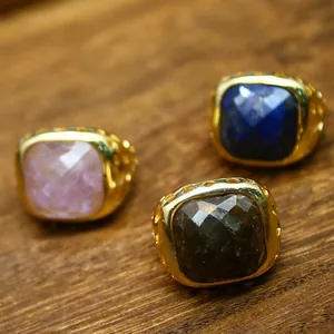 Primo piano di tre anelli placcati in oro 24 carati con varie pietre naturali dure