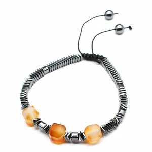 Vista macro de pulsera tejida a mano con galones de hematita y cuentas de ágata naranja