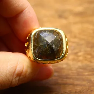 Primo piano di un anello placcato oro 24 carati con una grande pietra naturale scura.