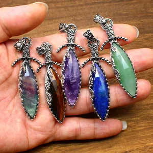 Close-up of five crystal sword pendants with faceted natural stones in a hand.