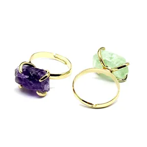 Close-up detail of raw amethyst and green fluorite stones in gold claw-set adjustable rings