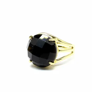 Detailaufnahme eines facettierten schwarzen Edelsteinrings mit vergoldeter Schiene.
