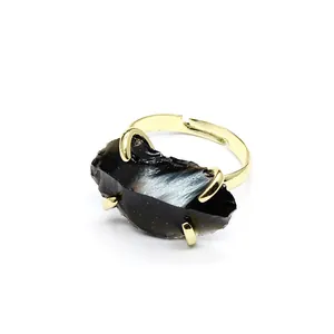 Close-up of raw black crystal ring with gold-plated claw setting and adjustable band