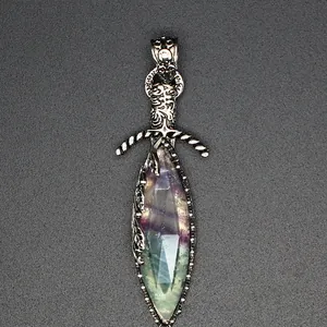 Close-up of a sword-shaped pendant featuring faceted natural stone and ornate silver detailing