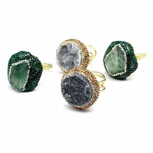 Detailed view of handmade adjustable rings with natural druzy agate and green stones.
