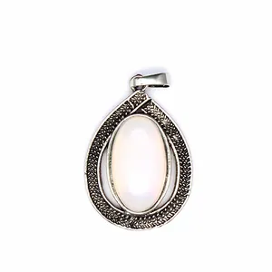 Macro view of a vintage teardrop pendant featuring an oval opal stone and engraved patterns