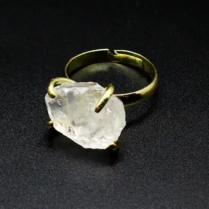 Macro view of a raw clear crystal stone set in a gold-plated adjustable claw ring