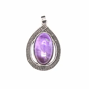 Close-up of a vintage purple amethyst crystal teardrop pendant in an ornate silver setting.