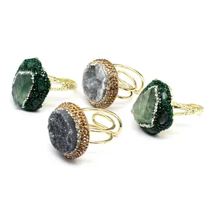 Detailed view of four chunky gold rings featuring natural druzy agate and green crystals