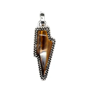 Macro detail of a retro lightning bolt pendant featuring a natural tiger eye stone inlay.